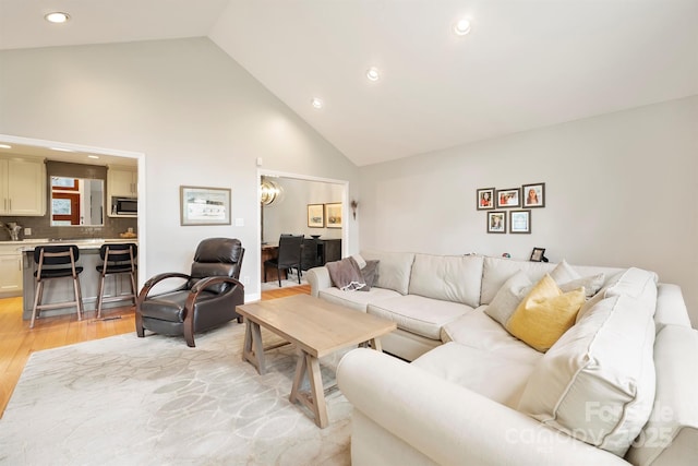 living area featuring high vaulted ceiling, recessed lighting, and light wood-style floors