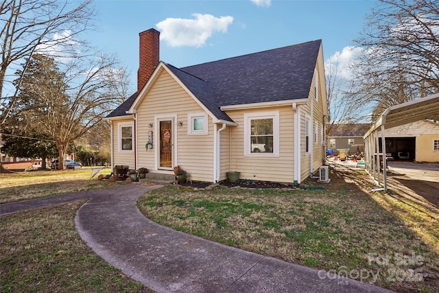 view of front of house with roof with shingles, a chimney, and a front yard