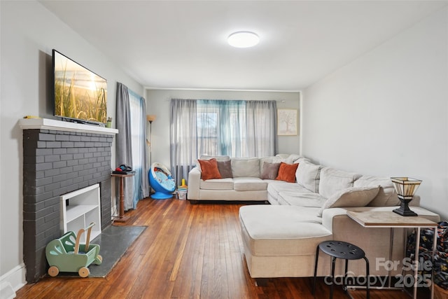 living area featuring wood-type flooring and a brick fireplace