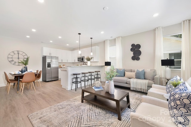 living room featuring light wood-style floors, plenty of natural light, baseboards, and recessed lighting