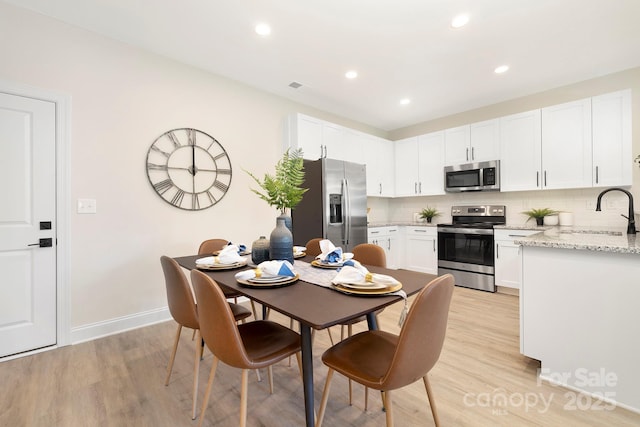 dining area featuring light wood finished floors, recessed lighting, and baseboards