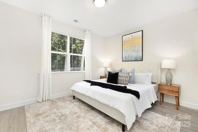 bedroom featuring light wood-style floors, visible vents, and baseboards