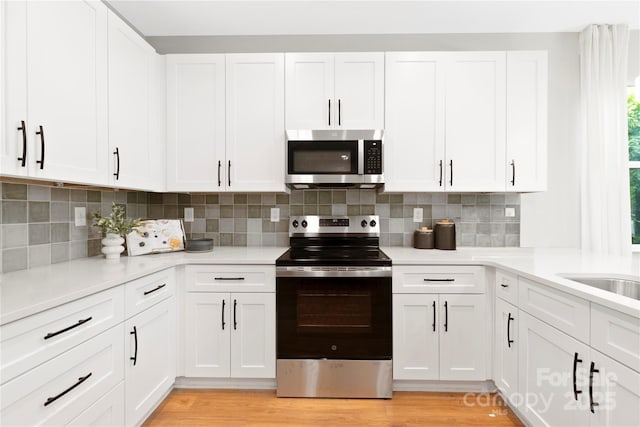 5404 Maplewood Ln, Charlotte, NC 28227 - kitchen with stainless steel appliances, white cabinetry, light countertops, decorative backsplash, and light wood-type flooring