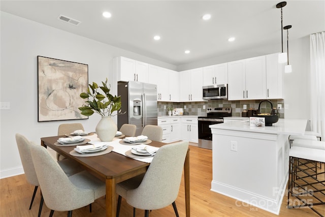 5404 Maplewood Ln, Charlotte, NC 28227 - kitchen featuring appliances with stainless steel finishes, a peninsula, a kitchen bar, backsplash, and light countertops