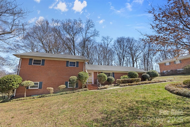 split level home featuring a front lawn and brick siding