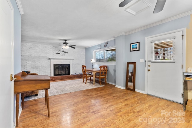 entrance foyer featuring a ceiling fan, light wood-style floors, ornamental molding, and a fireplace