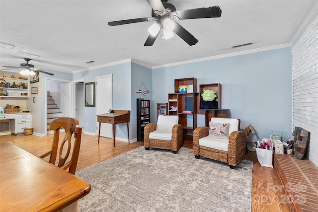 interior space with visible vents, a ceiling fan, wood finished floors, and crown molding