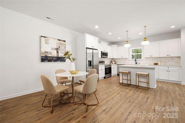 dining area with baseboards, light wood-type flooring, visible vents, and recessed lighting