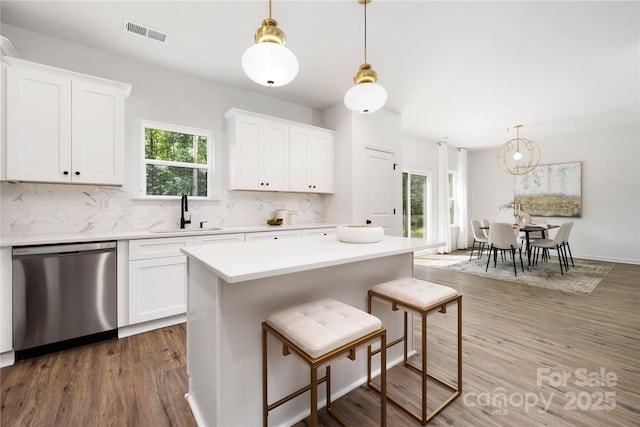 kitchen with a sink, white cabinets, light countertops, and stainless steel dishwasher