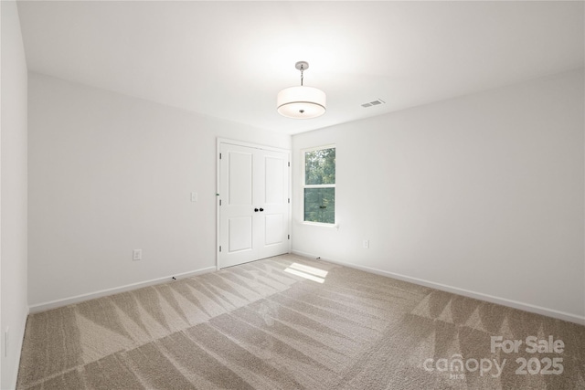 carpeted spare room with visible vents and baseboards