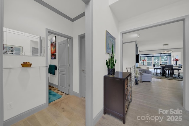 corridor featuring light wood-style floors and baseboards