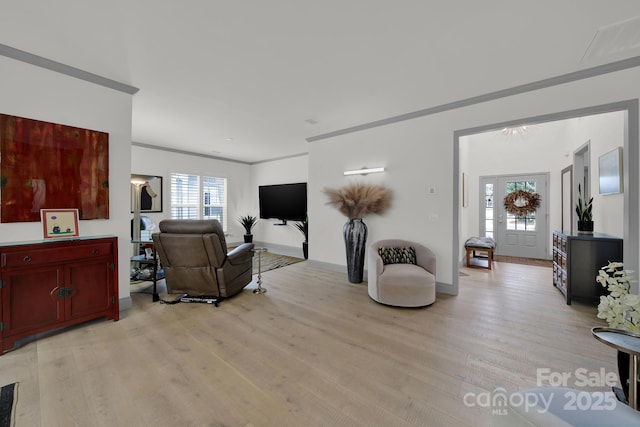 living room featuring light wood-style floors, baseboards, and ornamental molding