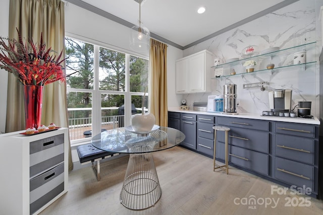 kitchen featuring light countertops, hanging light fixtures, light wood-style flooring, backsplash, and white cabinets