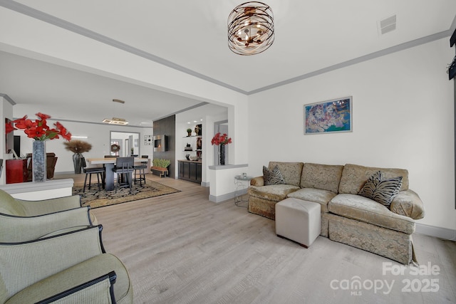 living area with baseboards, an inviting chandelier, visible vents, and light wood-style floors