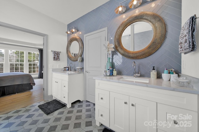 full bathroom featuring ensuite bath, two vanities, backsplash, and a sink