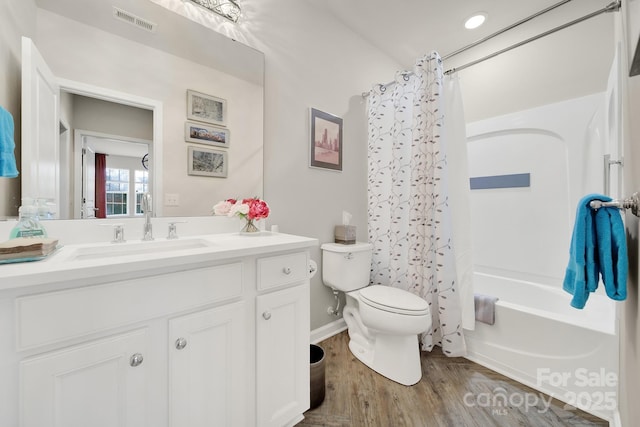 bathroom featuring toilet, wood finished floors, vanity, visible vents, and shower / bath combo