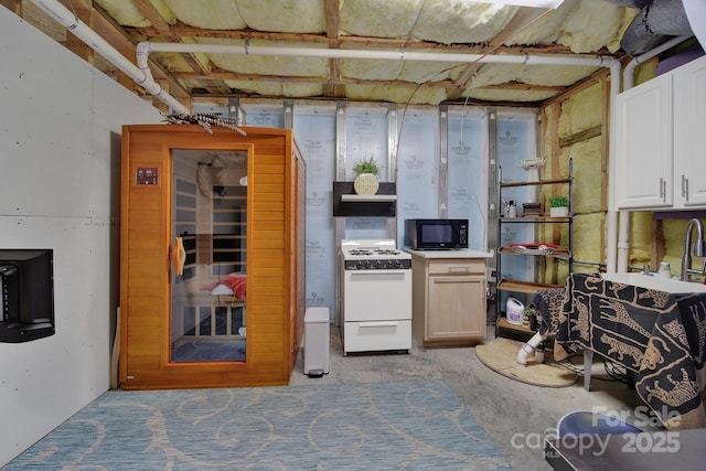 kitchen featuring black microwave, white cabinets, and white gas stove