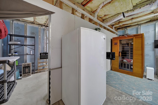 unfinished basement featuring freestanding refrigerator and heating unit