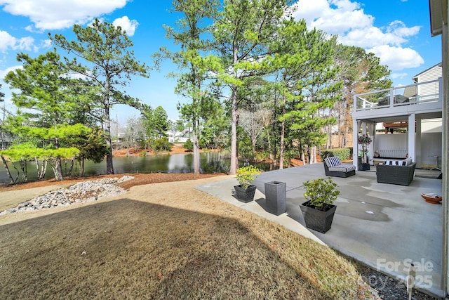 view of yard featuring a patio area, a water view, outdoor lounge area, and a balcony