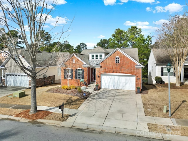 traditional home featuring a garage, concrete driveway, brick siding, and roof with shingles