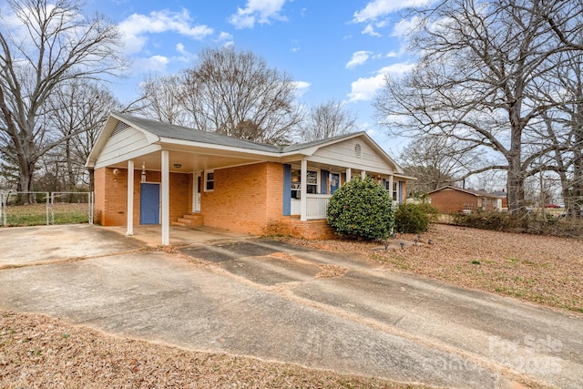 view of front facade featuring a carport, concrete driveway, brick siding, and fence