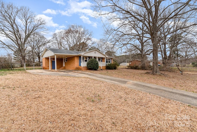 view of front facade with brick siding, driveway, and fence