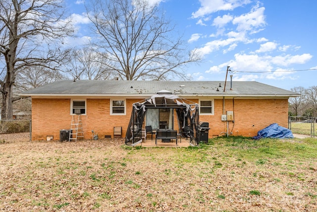 back of house featuring crawl space, brick siding, fence, and a gazebo