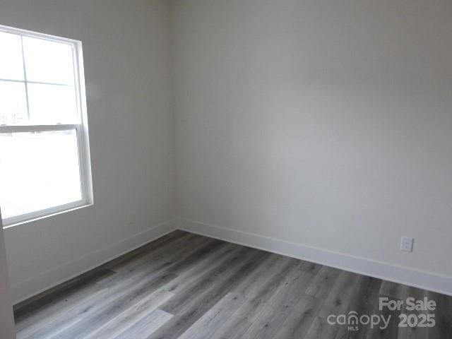 spare room featuring baseboards and wood finished floors