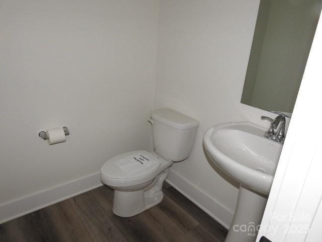 half bathroom featuring baseboards, toilet, and wood finished floors