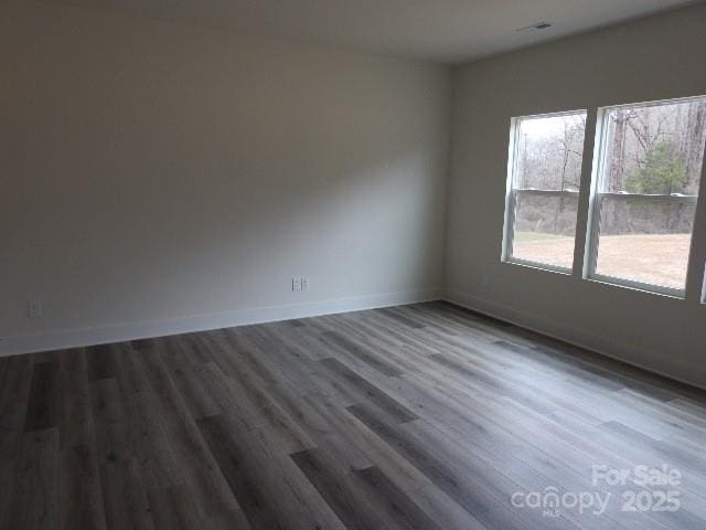 unfurnished room with dark wood-style flooring and baseboards