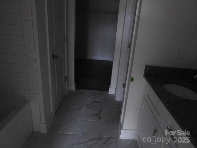 full bathroom featuring marble finish floor, a washtub, and vanity