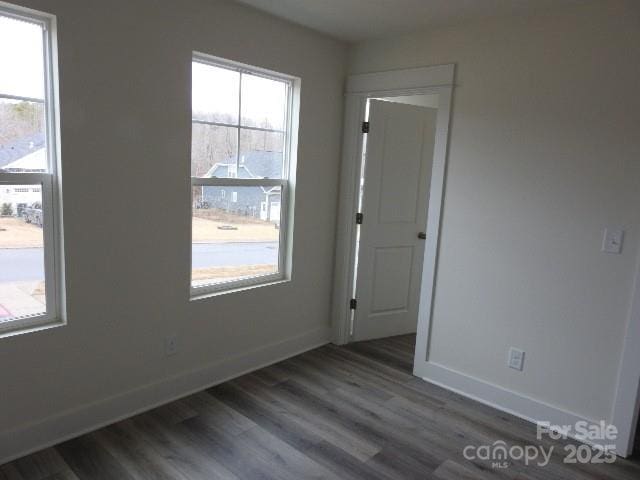 spare room featuring baseboards and dark wood finished floors