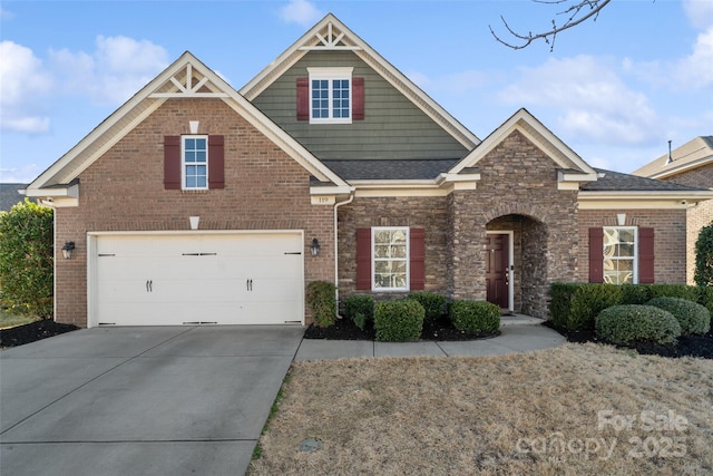 craftsman inspired home featuring a shingled roof, concrete driveway, and brick siding