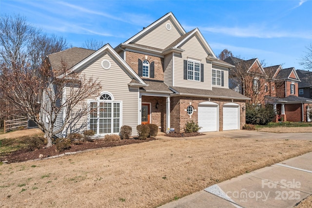 traditional home featuring brick siding, roof with shingles, a front yard, a garage, and driveway