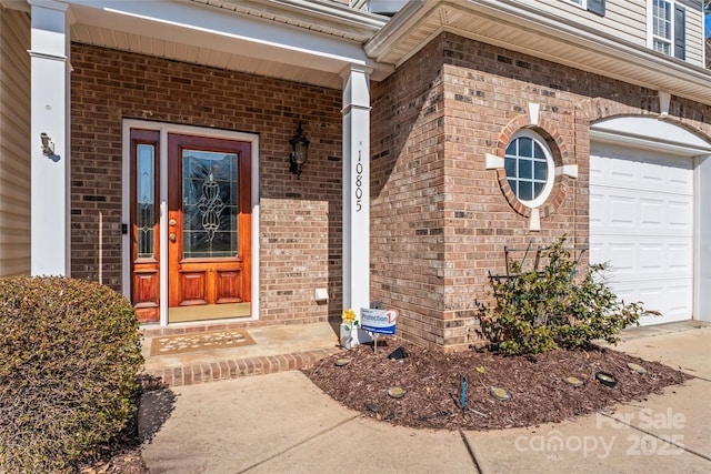 doorway to property with brick siding and an attached garage