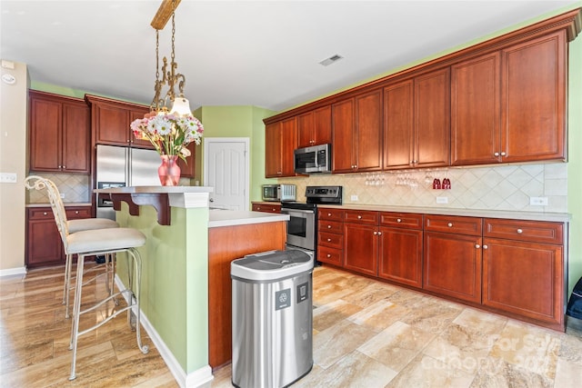 kitchen featuring a breakfast bar area, stainless steel appliances, light countertops, visible vents, and a kitchen island