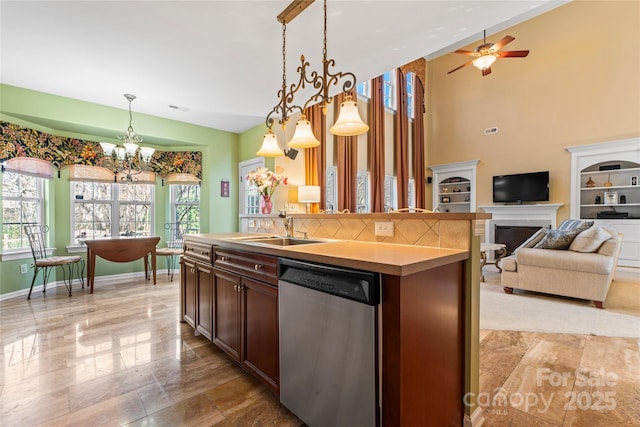 kitchen featuring decorative light fixtures, open floor plan, a sink, an island with sink, and dishwasher