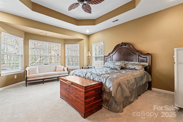 bedroom featuring a raised ceiling, visible vents, a ceiling fan, light carpet, and baseboards