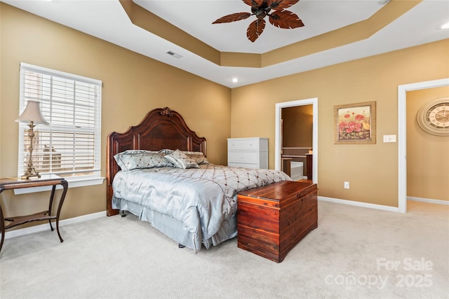 bedroom with light carpet, baseboards, visible vents, ensuite bathroom, and a tray ceiling