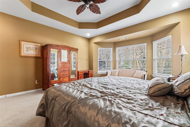 carpeted bedroom featuring a raised ceiling, a ceiling fan, and baseboards