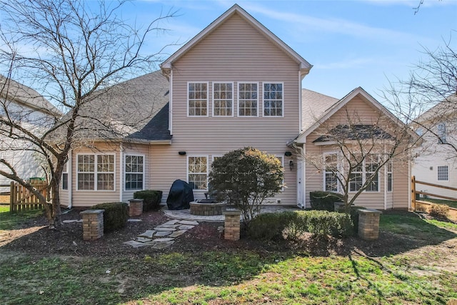 rear view of house featuring roof with shingles and fence