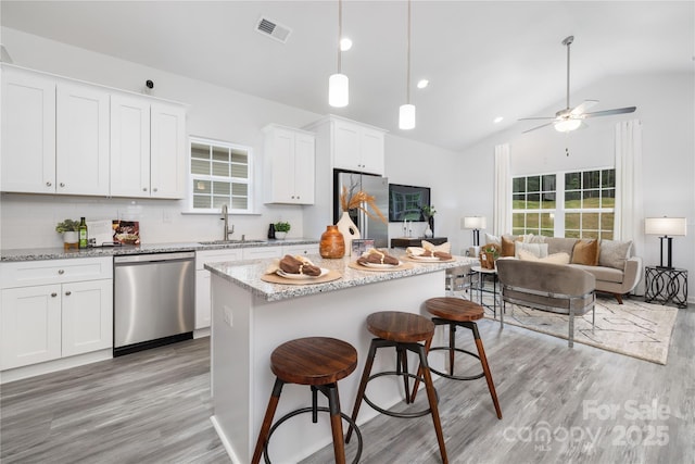 kitchen featuring a kitchen island, stainless steel appliances, a sink, and open floor plan