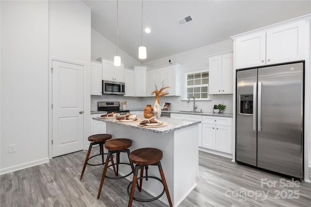 kitchen with a center island, pendant lighting, visible vents, appliances with stainless steel finishes, and a sink