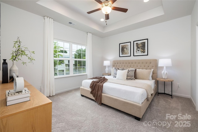 bedroom with visible vents, a raised ceiling, baseboards, ceiling fan, and carpet