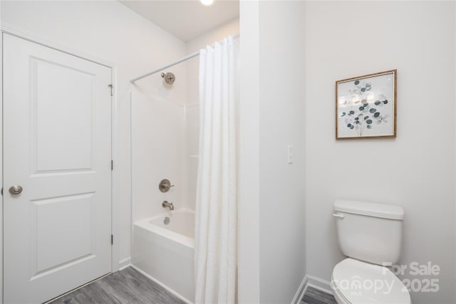 bathroom with wood finished floors, shower / bath combination with curtain, and toilet