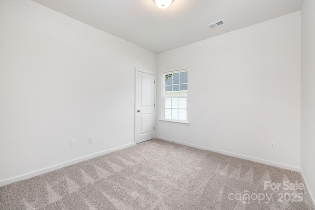 empty room featuring light colored carpet, visible vents, and baseboards