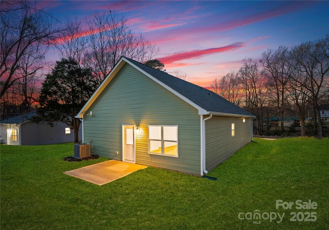 back of property at dusk with a patio area, central AC unit, and a yard