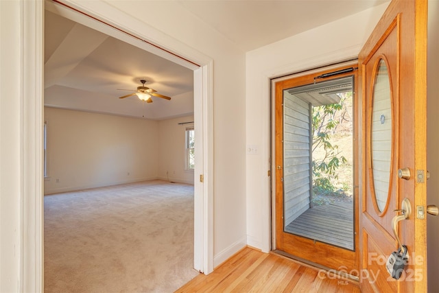 interior space featuring a ceiling fan, light wood-type flooring, light carpet, and baseboards