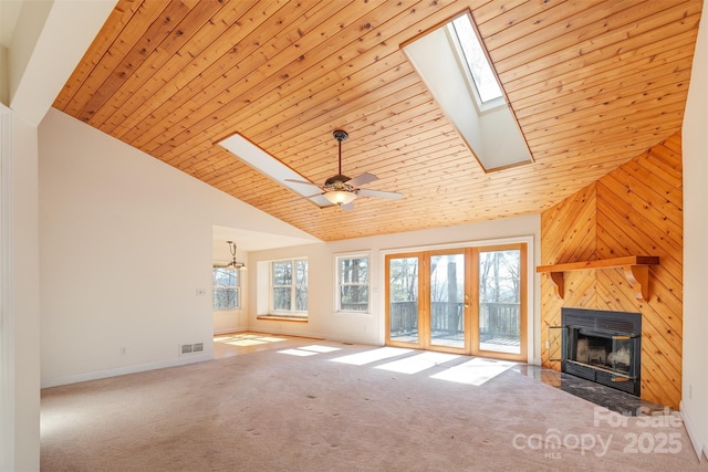 unfurnished living room featuring carpet floors, a skylight, a fireplace with flush hearth, wood ceiling, and high vaulted ceiling