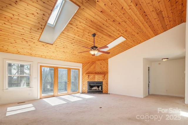 unfurnished living room featuring carpet floors, a skylight, a tiled fireplace, wood ceiling, and high vaulted ceiling